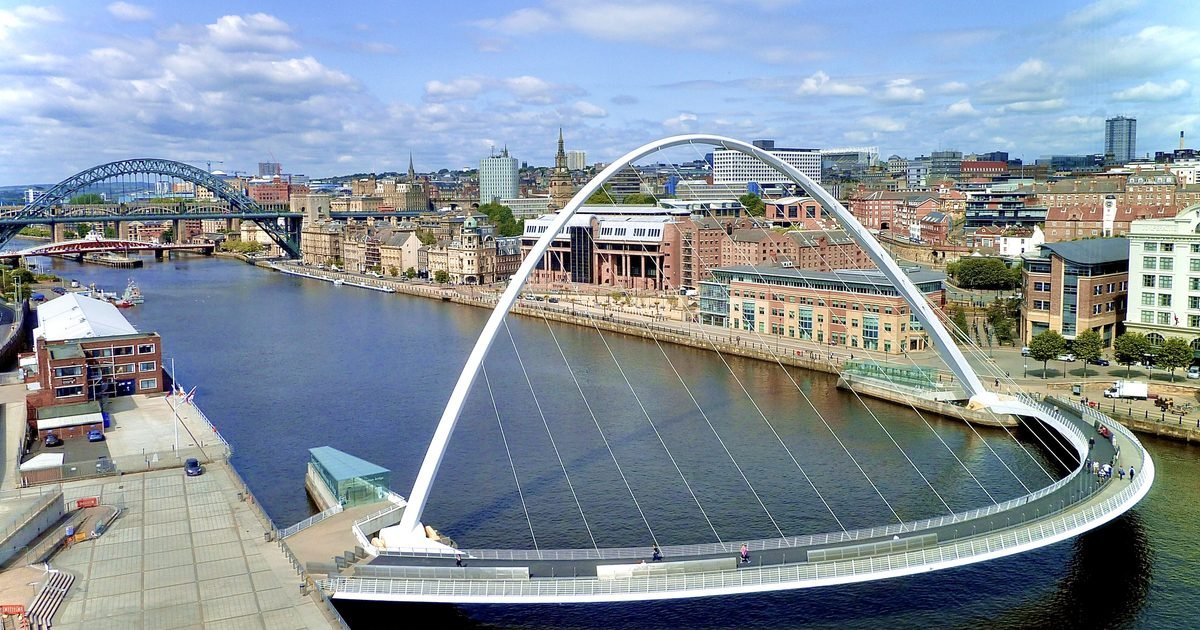 Newcastle Quayside showing the Tyne Bridge and the curved Gateshead Millennium Bridge at twilight